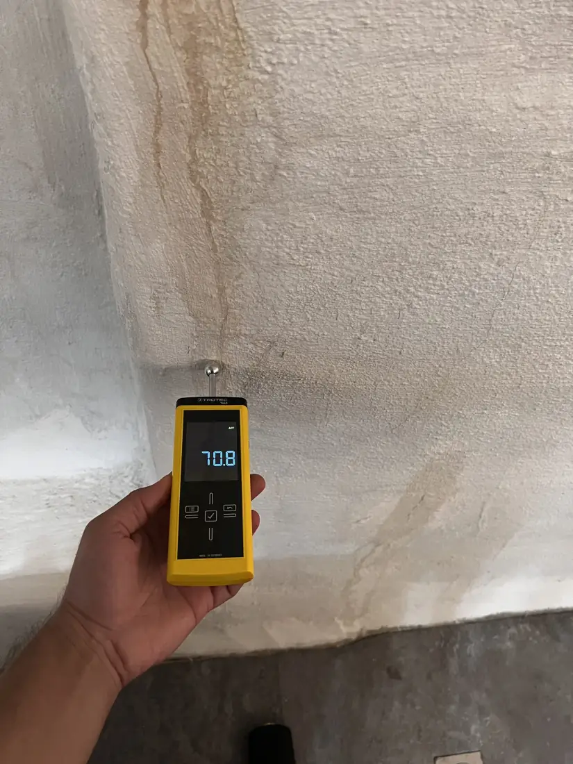 Vochtstrepen op de muur, de vochtmeter toont 70,8