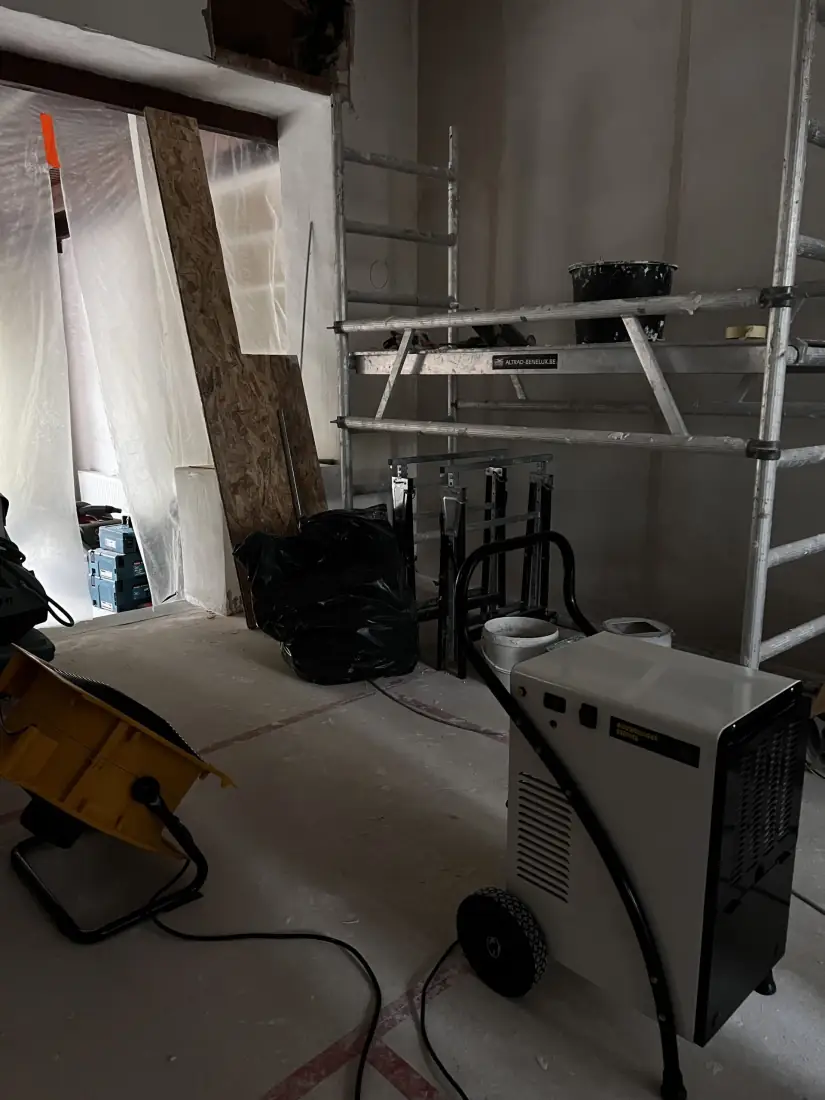 Droger en ventilator naast een met folie afgeschermde opening