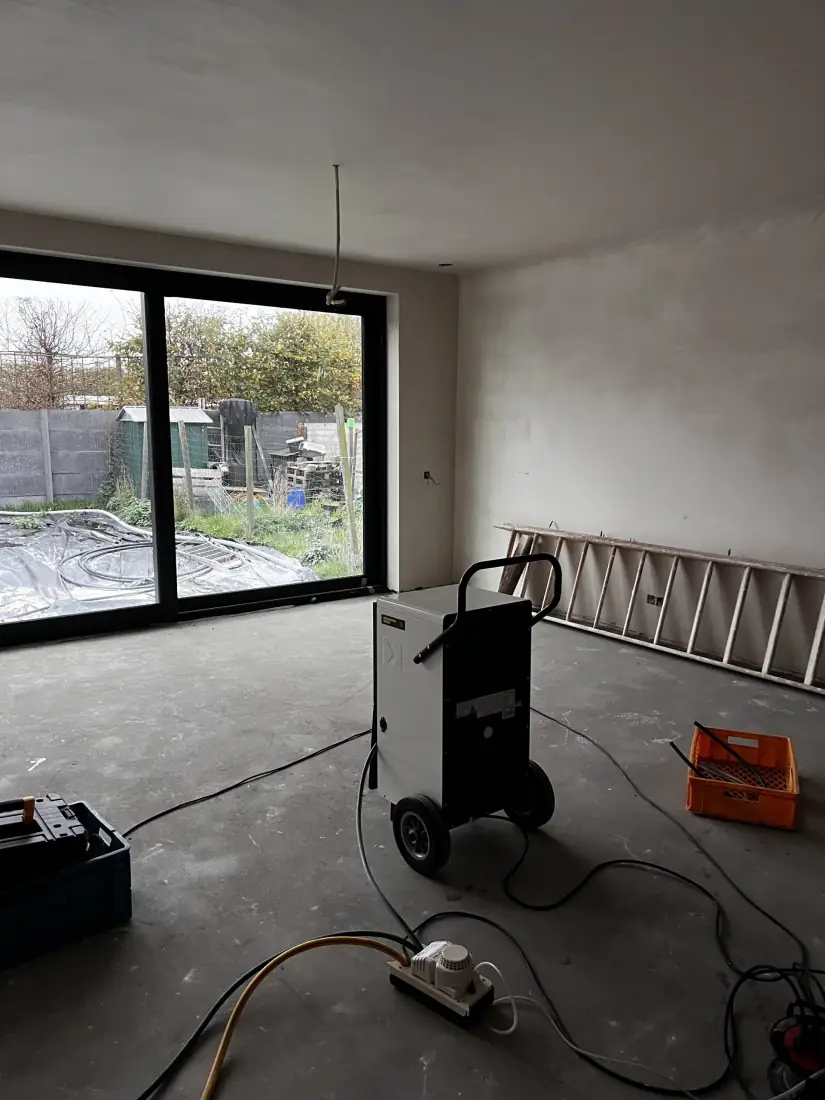 Droging van de woonkamer met bouwdroger en zicht op de tuin