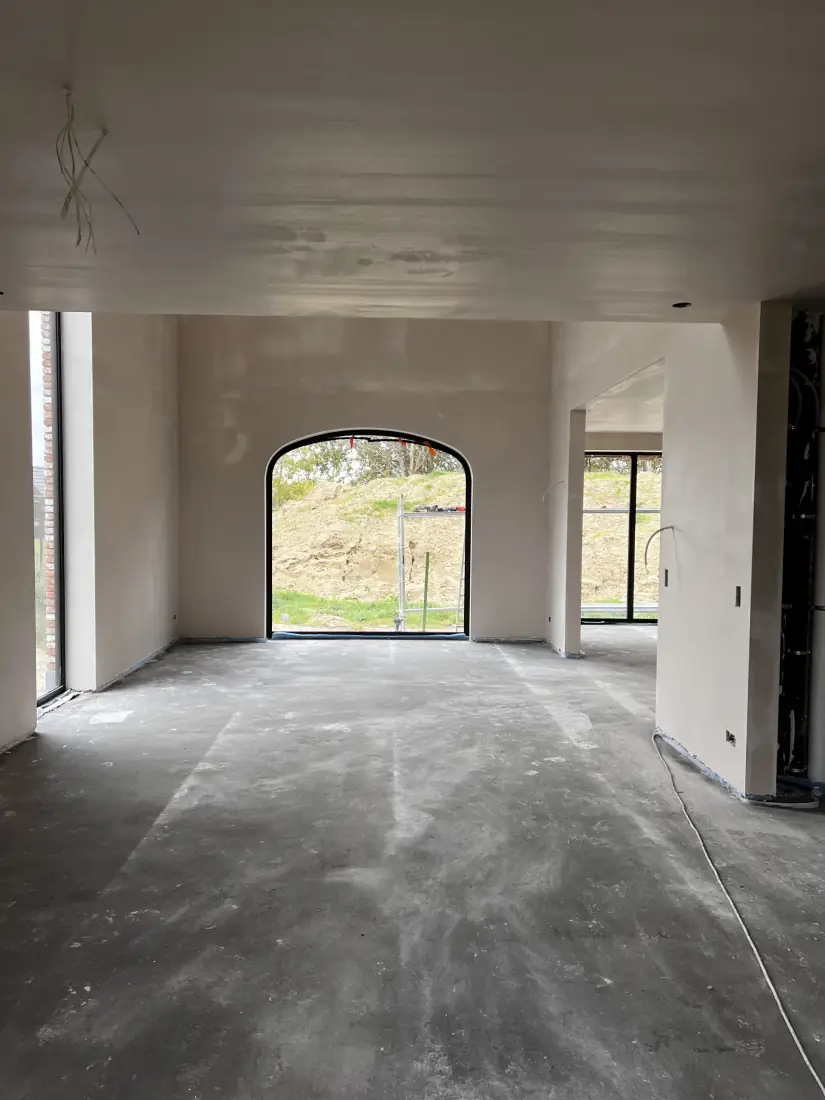Gepleisterde leefruimte met boograam, gereed voor afwerking