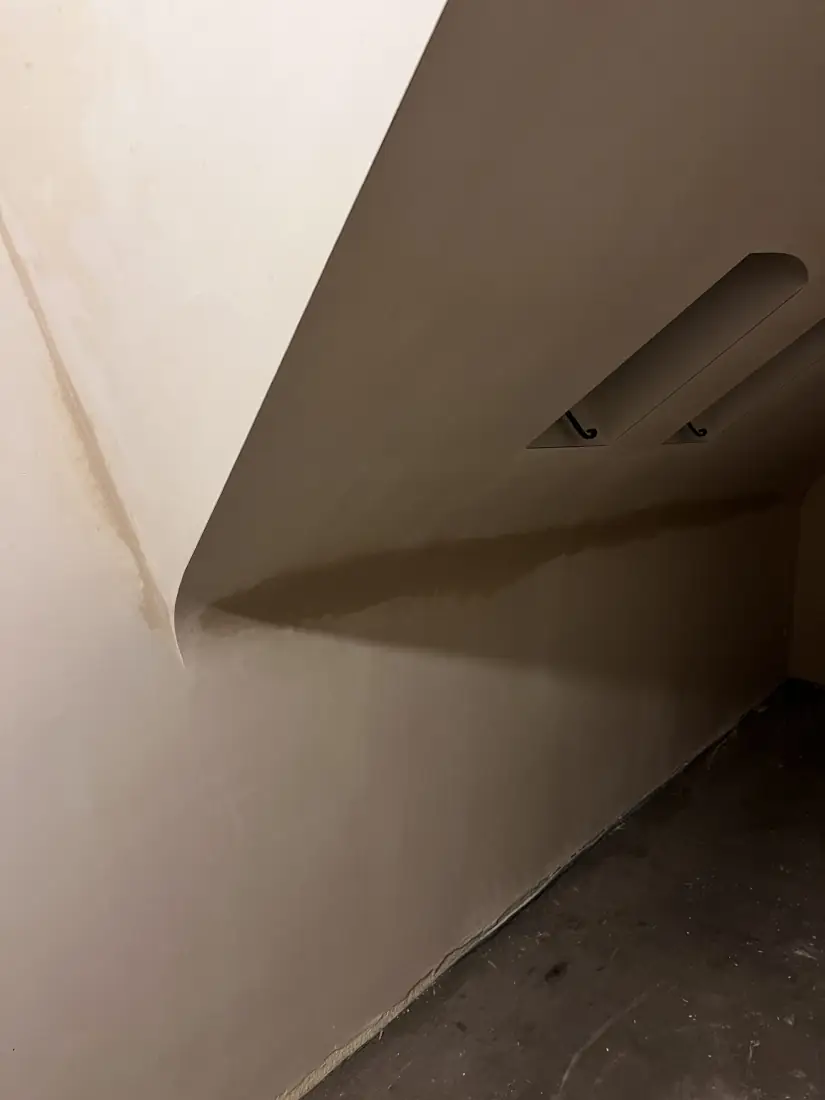 Vers pleisterwerk met een vochtrand tegen het plafond